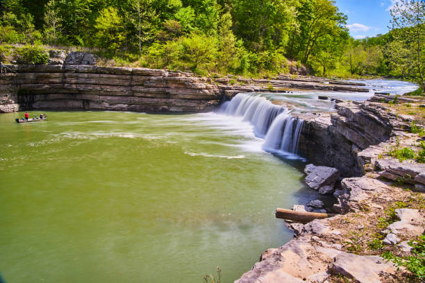 istock Fisherman on boat in gorge next to large waterfall in forest 1490383489