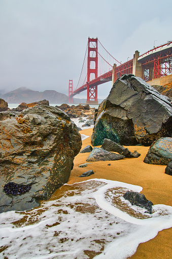 Image of Foggy morning at Golden Gate Bridge from sandy beaches with ocean waves and rocks