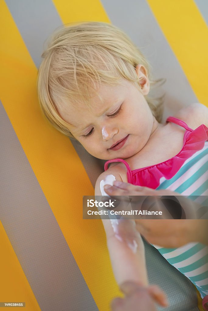 Baby waiting while mother applying sun block creme on arm Applying Stock Photo
