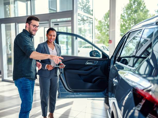 Saleswoman helping the male customer to choose a new car stock photo