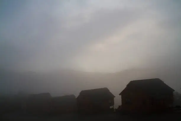 Photo of Haunting grey hazed image of cabins with a mountain looming in the background