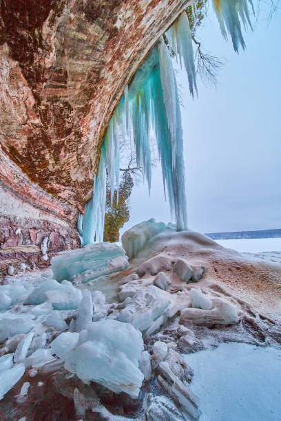 istock Ice cave opening on rocks and lake with blue icicles 1490388991