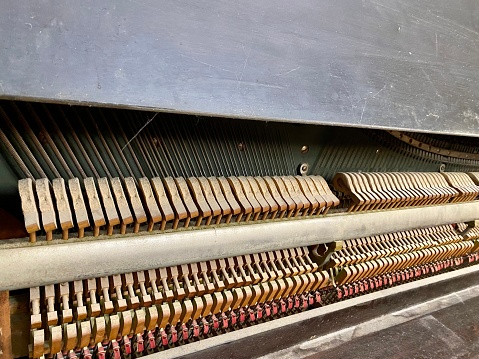 Inner workings of an antique upright piano. Hammers, wires and tuning pins