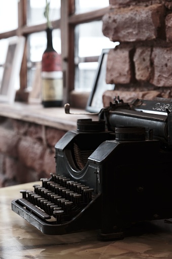 A vintage typewriter on a wooden table illuminated by natural light coming through a nearby window