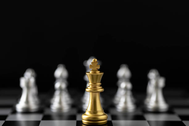 istock Golden King chess standing in front of other chess on chess board. 1490392978
