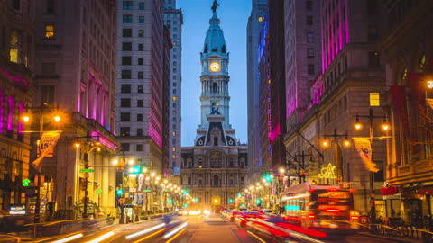 Time lapse of Philadelphia's landmark historic City Hall with traffic car and crowd pedestrian tourist crossroad city street at night in Pennsylvania, United States