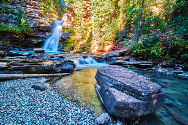 istock Large boulder in riverbed by blue majestic waterfall in canyon 1490393904