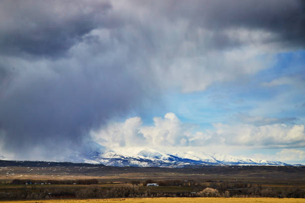 istock Large dark storm overtaking fields and white snowy mountains 1490394096
