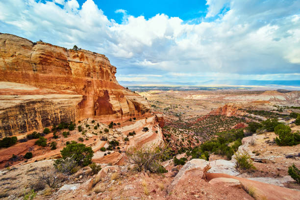 istock Large red cliffs in desert canyon with open valley and clouds 1490394978