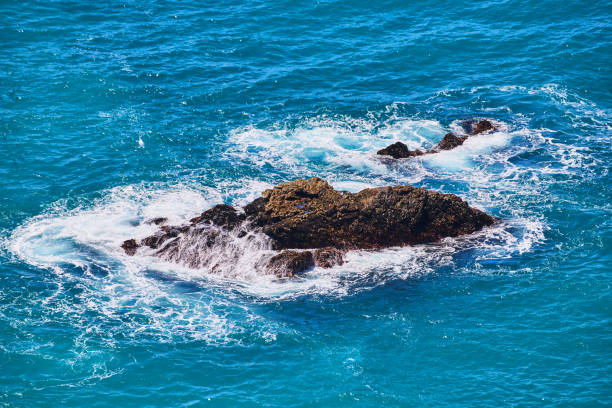 Image of Large rocks in ocean water with waves crashing into them