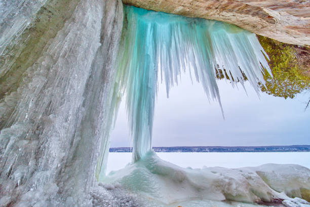 istock Large sharp blue icicles hanging from rocks next to frozen lake in winter 1490395064