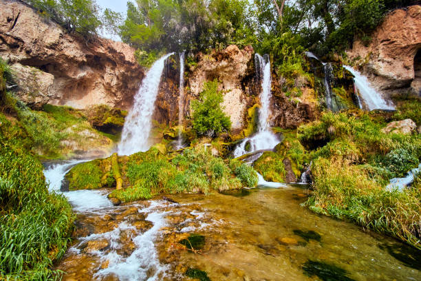 istock Large waterfall pouring into river over cliffs with lush green plants 1490395395