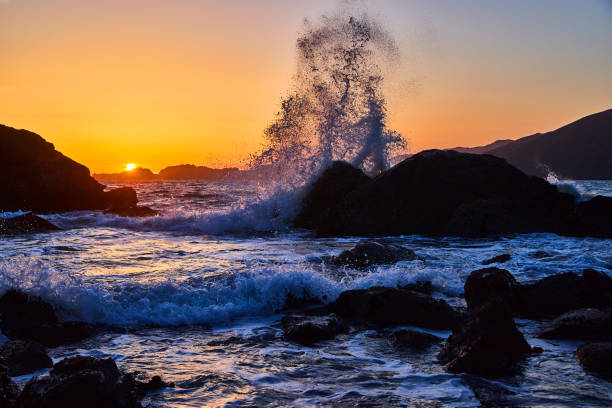 istock Large wave crashing into rocks on beach during gorgeous sunset 1490395412