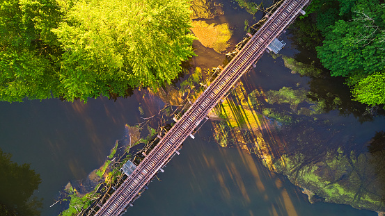 Image of Light of sunset aerial looking down at railroad tracks over river