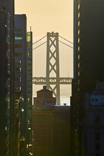Image of Oakland Bay Bridge in San Francisco during golden hour between skyscrapers