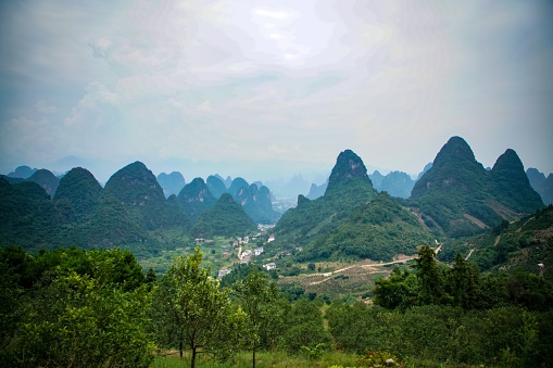 A scenic view of lush greenery and majestic mountains in the background. Guilin, China.