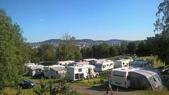 Parking of campers in a summer camp against the background of green trees and blue sky