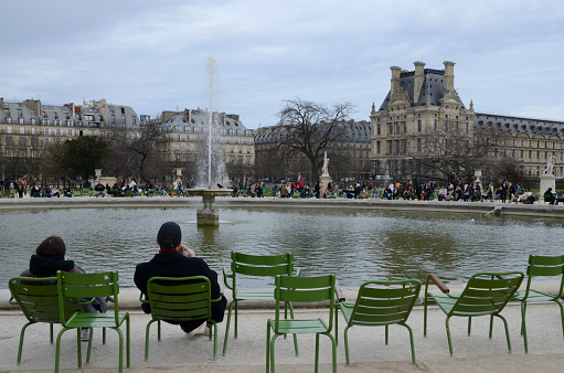 Paris, France - March 20, 2023: People around big pond at the Tuileries Garden in Paris, France.