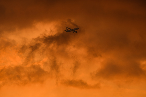 airplane flies over the spectacular orange sky and clouds