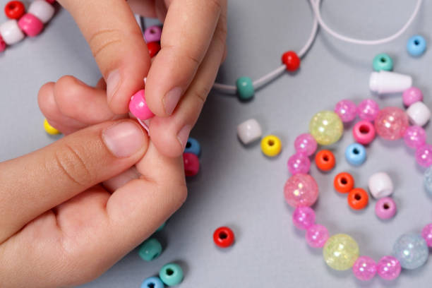 istock Making a bracelet from colored beads, children's hands close-up 1490405520