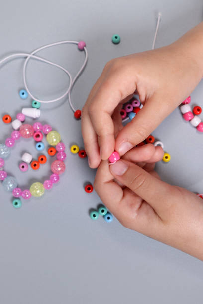 istock Making a bracelet from colored beads, children's hands close-up. vertical orientation 1490405559