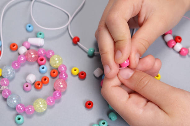 istock Girl making a bracelet from colored beads close-up 1490405574