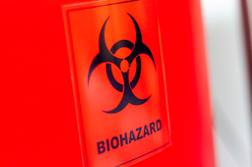 The international symbol for biohazard on a biohazardous waste container in a scientific research lab.