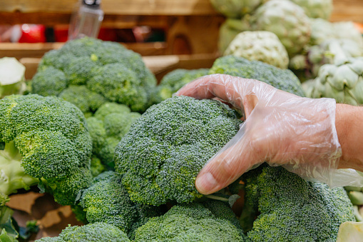 Man's hand holding broccoli. A man buys vegetables in an organic and ecological store.