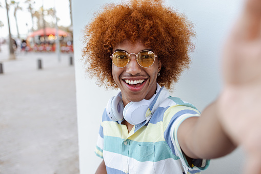 Portrait of a positive Black man with wireless headphones looking at the camera