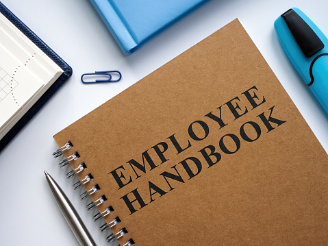 Employee handbook near notepads and pen.