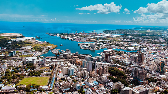 An aerial view of the port in Port Louis with blue Indian Ocean waters and a clear blue sky. \n- Port Louis, Mauritius