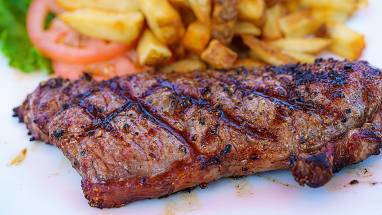 Sliced Steak Ribeye with french fries on serving board block on wooden background