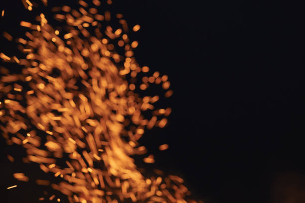 blurred firecamp sparks over night sky, black background