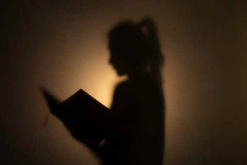 Silhouette young woman reading a book.