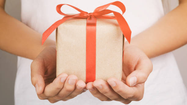istock young female hands holding gift box with red ribbon 1490429515