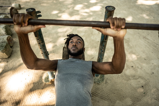 Young man doing bench press in the park