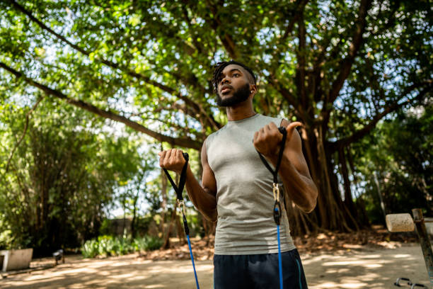 istock Young man exercising with resistance band in the park 1490432733