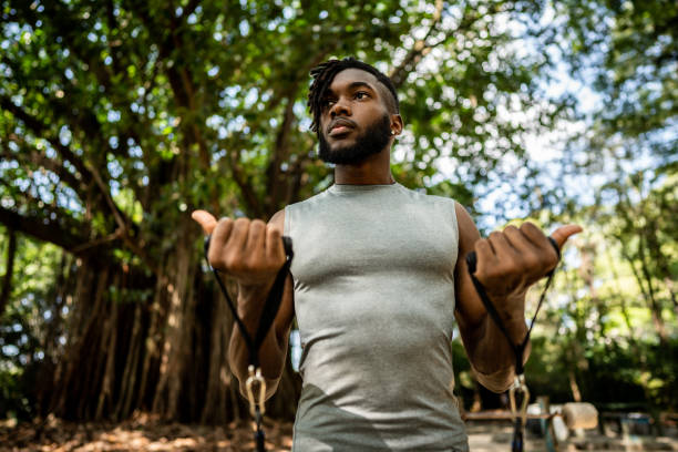 istock Young man exercising with resistance band in the park 1490432776