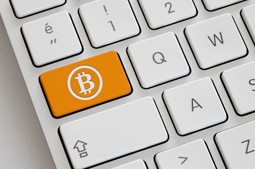 Orange colored Crypto Currency Button on a computer keyboard.