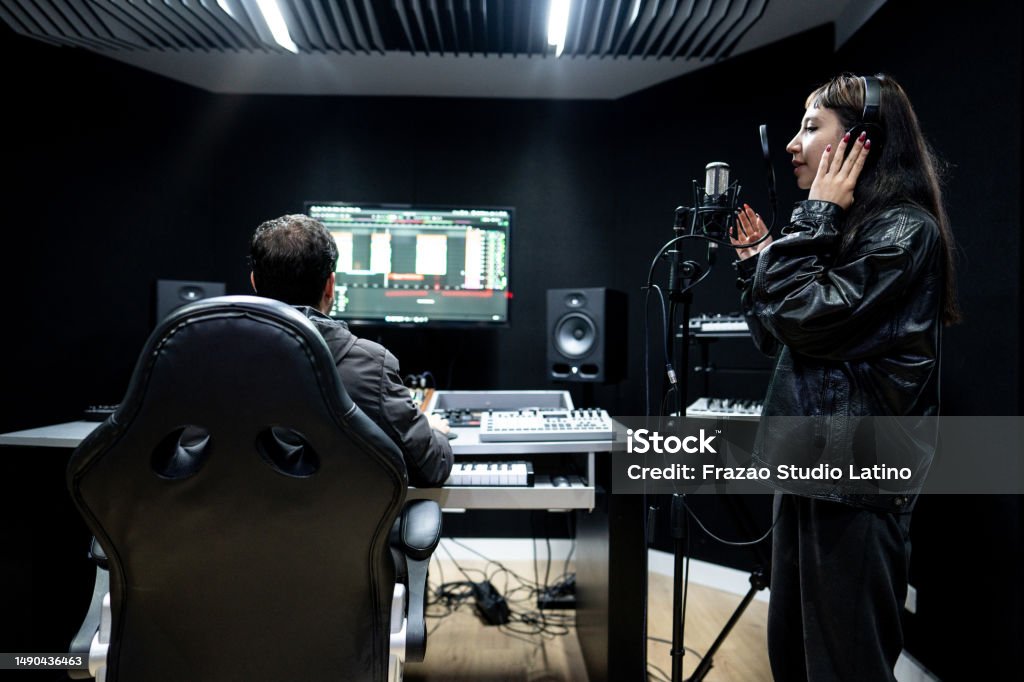 Singer young woman singing next to her producer in the recording studio Music Stock Photo