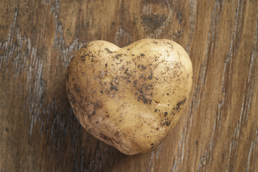 heart shaped potato on oak table, organic food