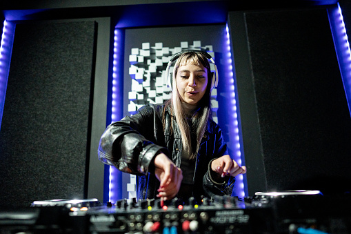 music controller DJ mixer in a nightclub at a party against the background of blurred silhouettes of dancing people