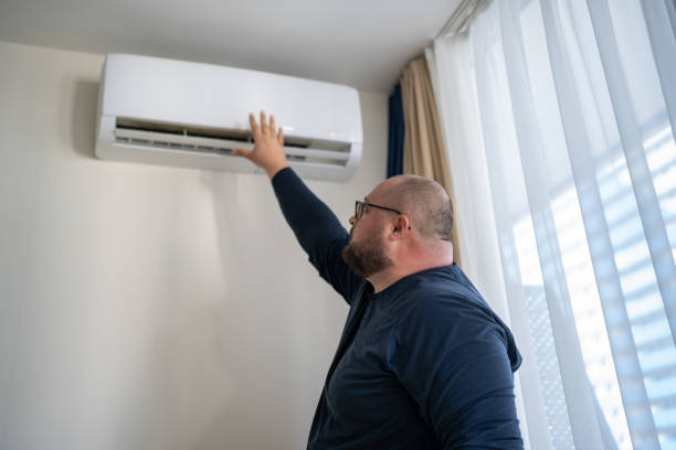 istock Man checking working air conditioner touching air by hand in summer hot time. 1490439881