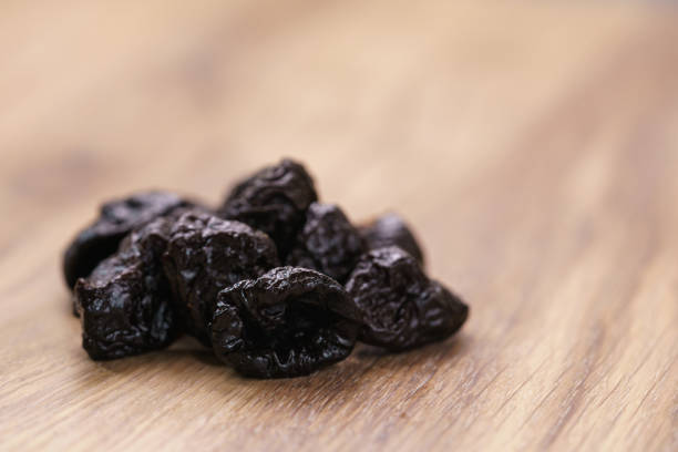 dried prunes on oak wood table, selective focus