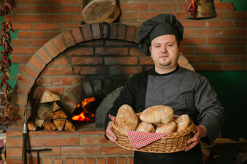 Baker holding the fresh baked bread loaf , just baked in the brick oven