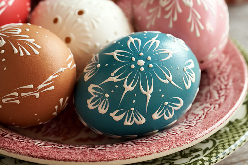 Colorful Easter eggs with wax ornaments on a red plate