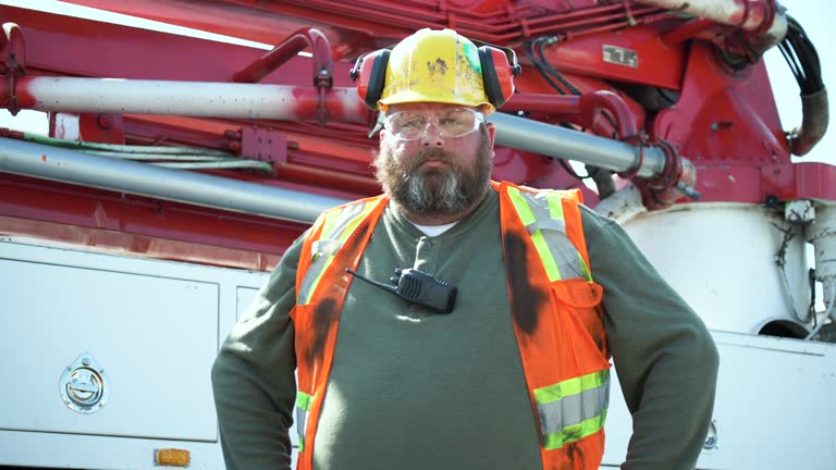 Construction worker standing by concrete pump truck