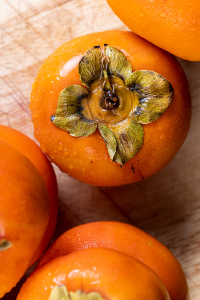 滴で覆われた熟したオレンジ色の柿 - autumn market freshness vertical ストックフォトと画像