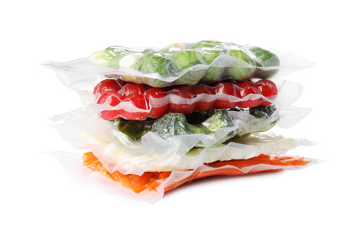 Stack of vacuum packs with different food products on white background