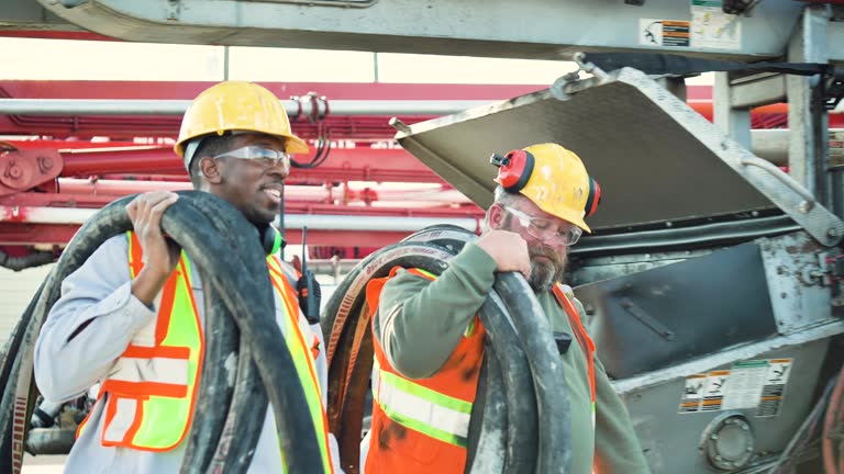 Two construction workers carrying concrete pump hoses